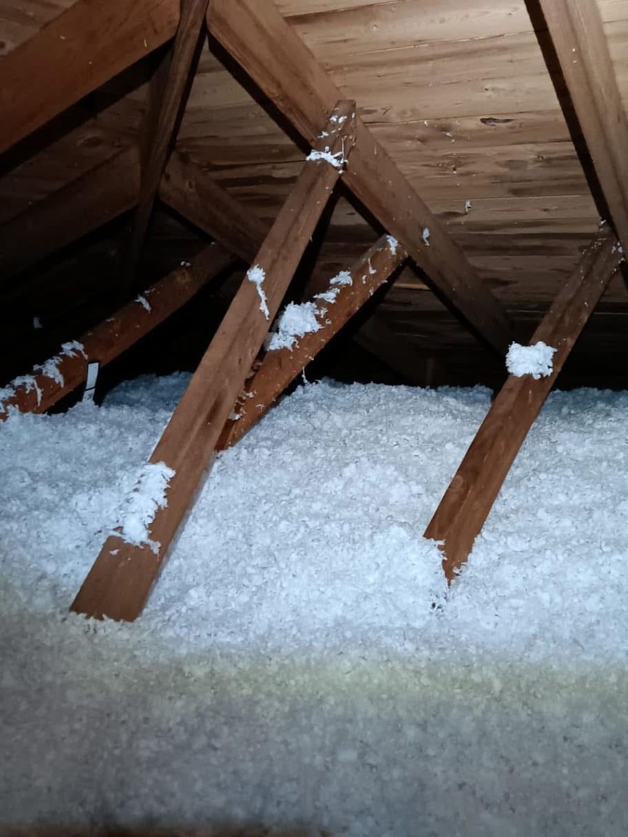 Even layer of fresh blown-in insulation covering an attic floor between roof rafters