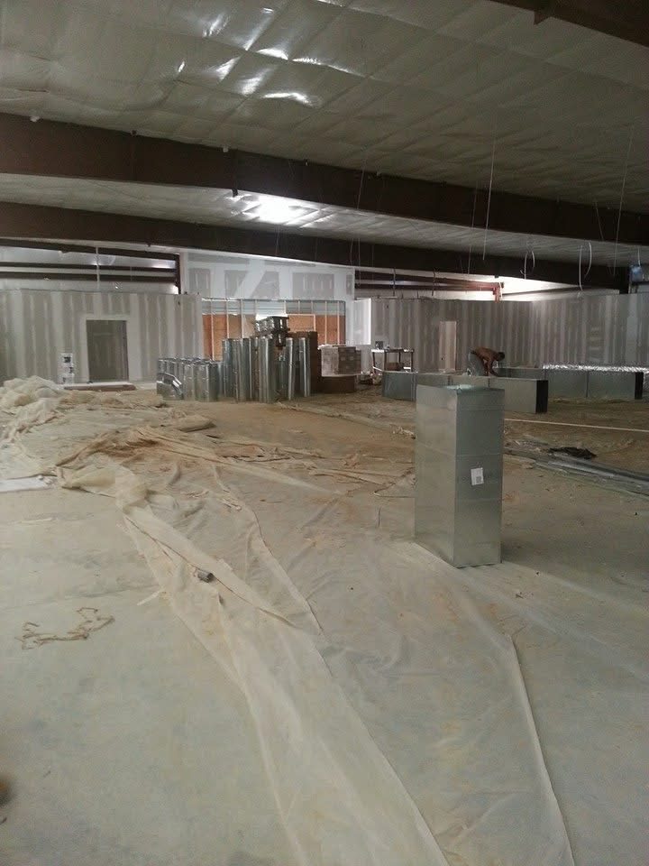 Custom sheet-metal ductwork being installed across the ceiling of a large commercial building