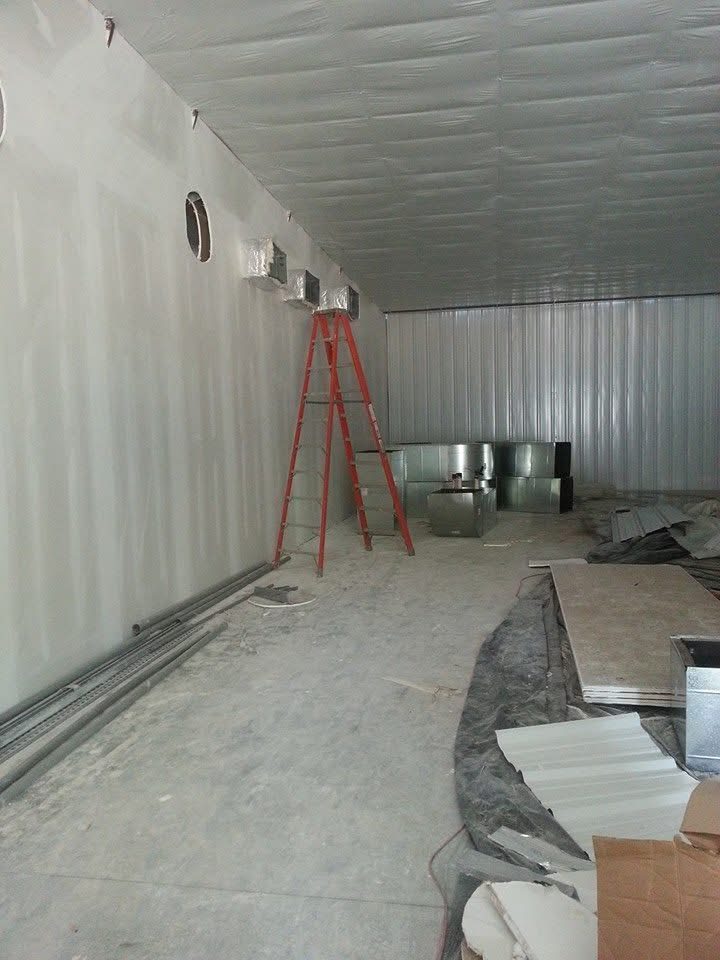 Insulated ductwork and sheet-metal plenums being installed high in a commercial building