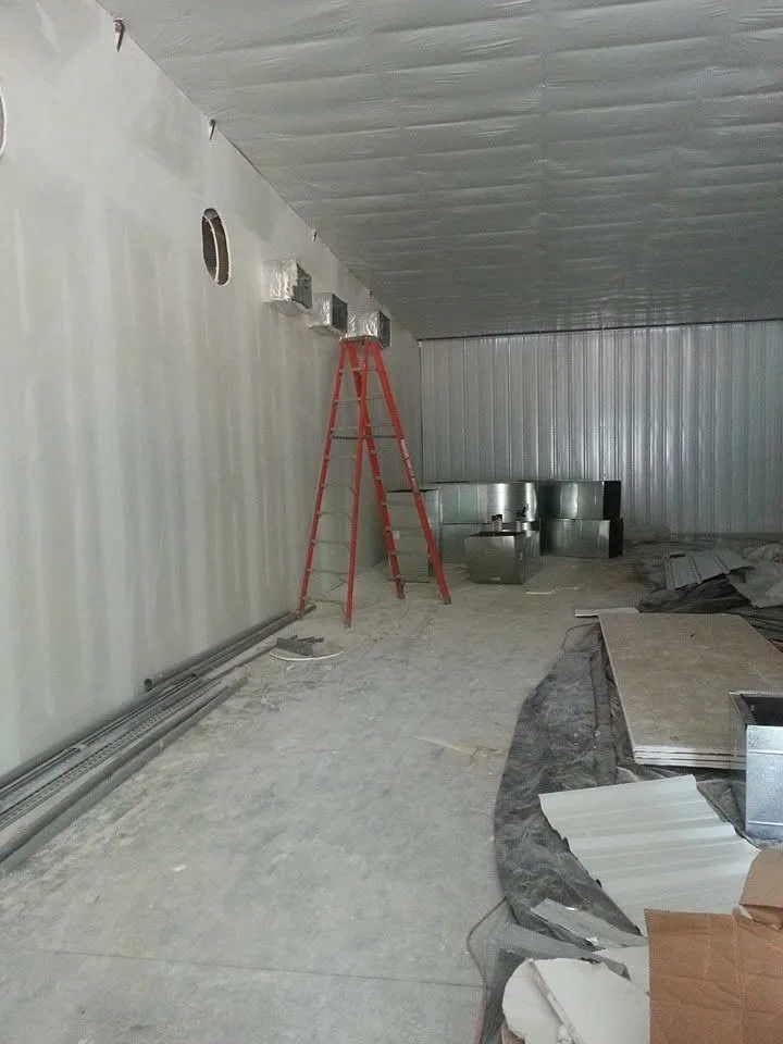 Insulated ductwork and sheet-metal plenums being installed high in a commercial building