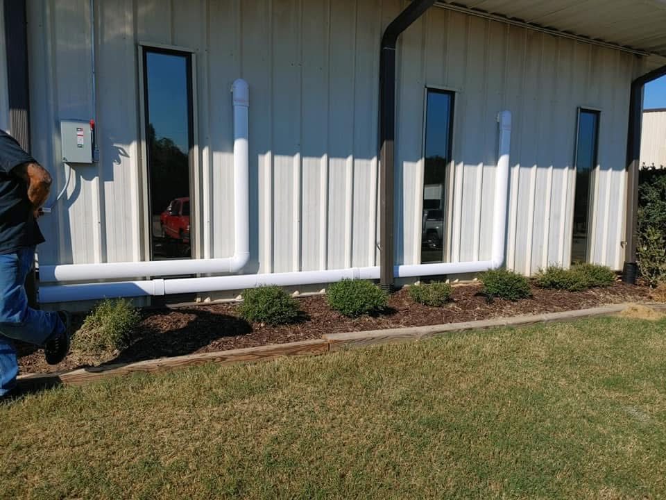 Neatly run white PVC line-set chases along the exterior wall of a commercial metal building