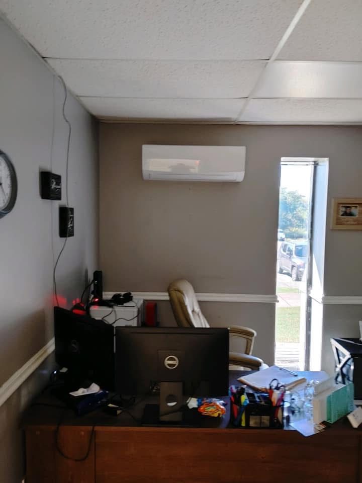 Ductless mini-split air handler mounted high on an office wall above a desk