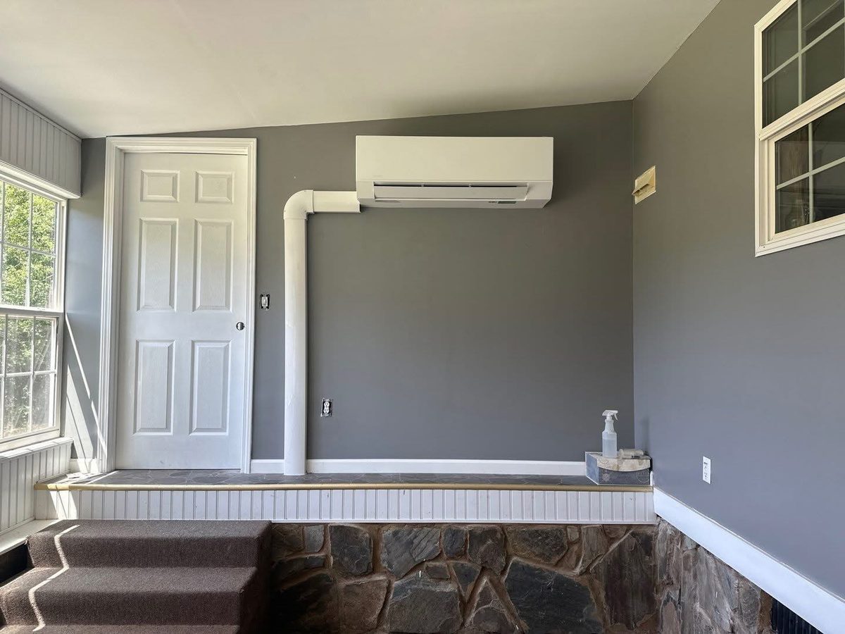 Wall-mounted ductless mini-split with neatly run line-set cover in a stone-accent room