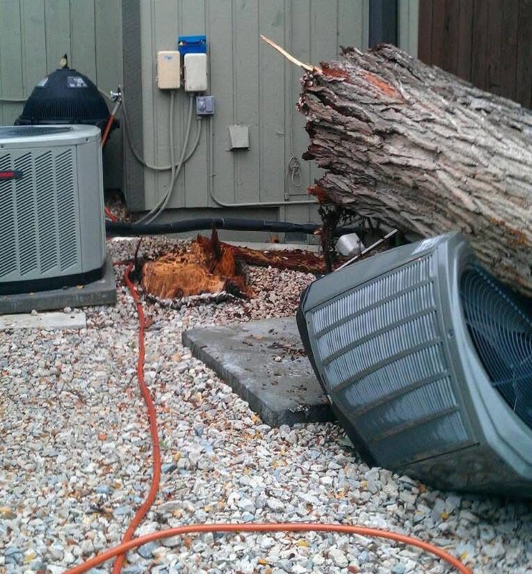 Outdoor AC condenser knocked over by a fallen tree, before storm-damage replacement