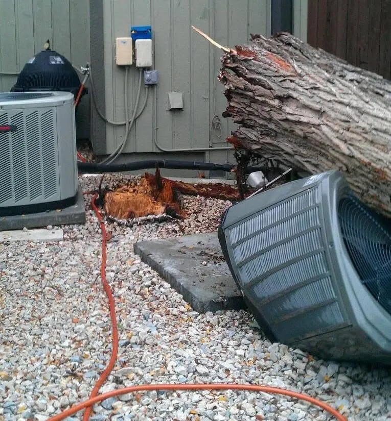 Outdoor AC condenser knocked over by a fallen tree, before storm-damage replacement