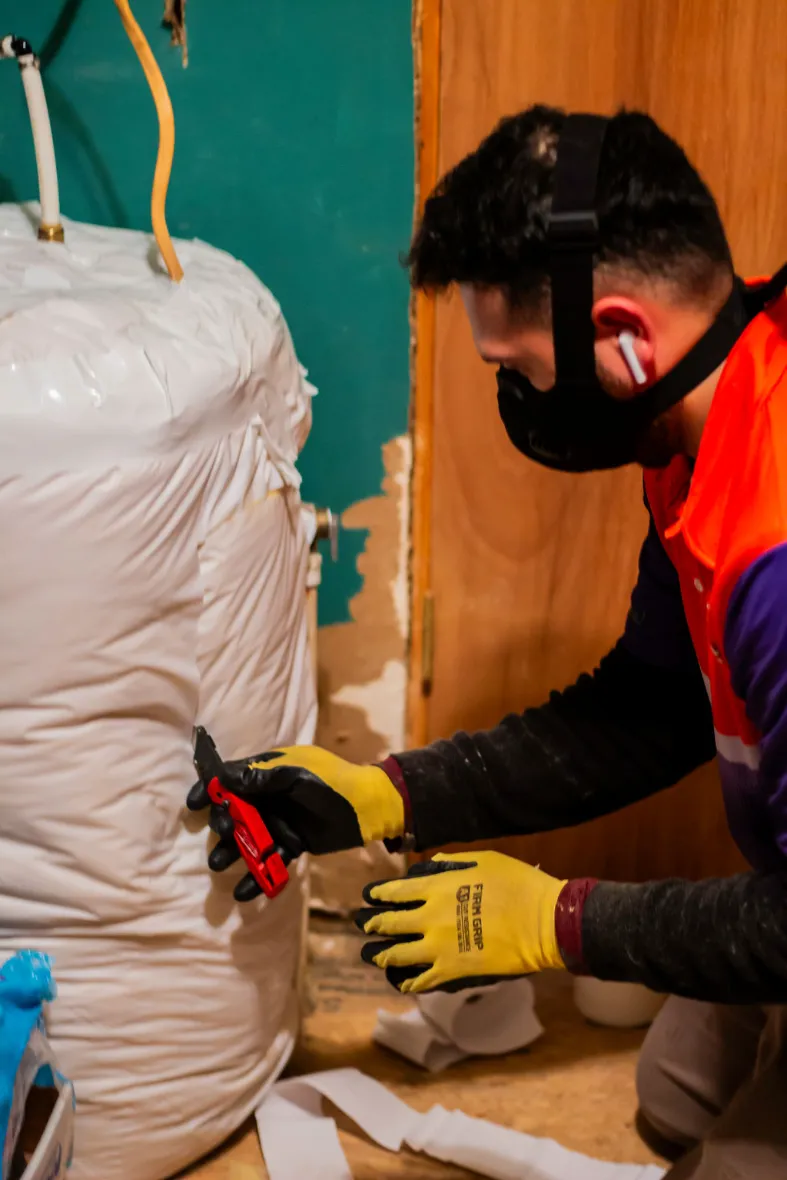 Anderson technician in a respirator preparing insulation for installation
