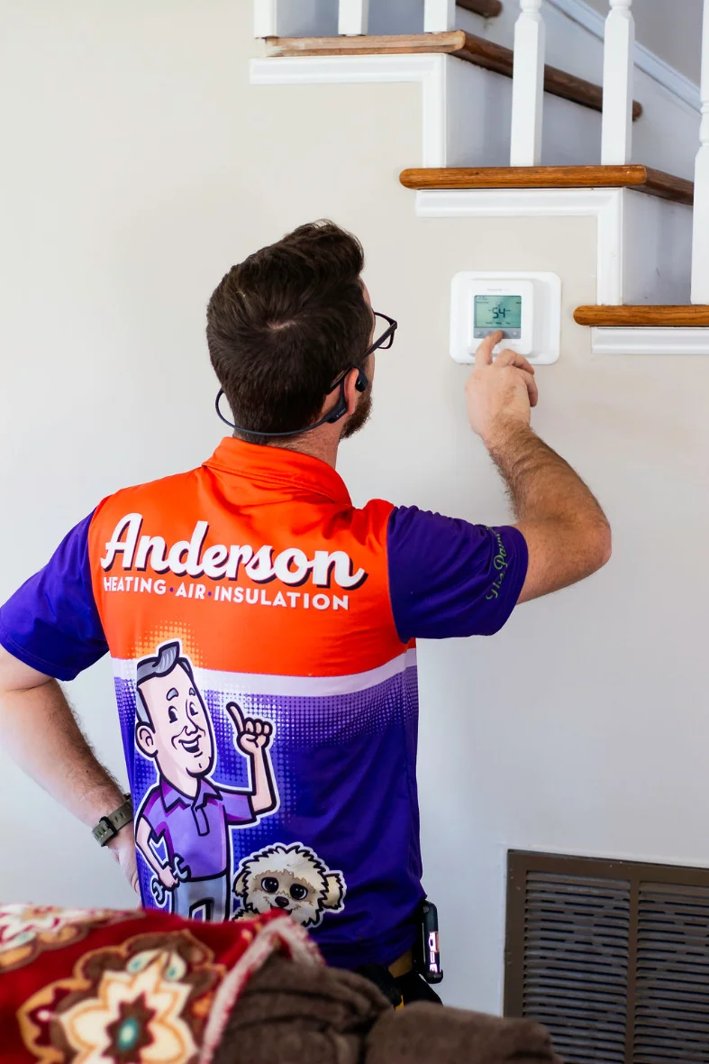 Anderson technician adjusting a homeowner’s wall thermostat