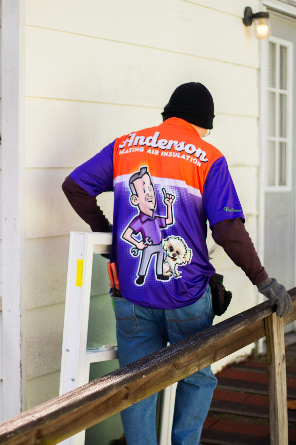 Anderson Heating, Air & Insulation technician carrying a new window unit on a porch ahead of installation — Anderson Heating, Air & Insulation serves Cartersville and Bartow County with HVAC, insulation, and windows.