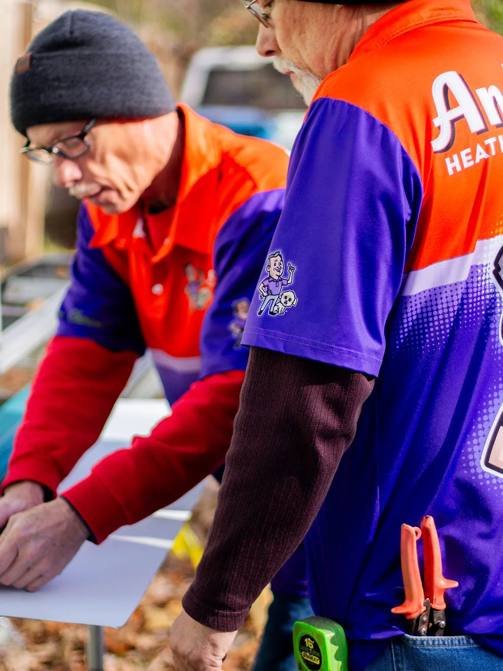 Two veteran Anderson installers working a sheet of trim material together on a job site