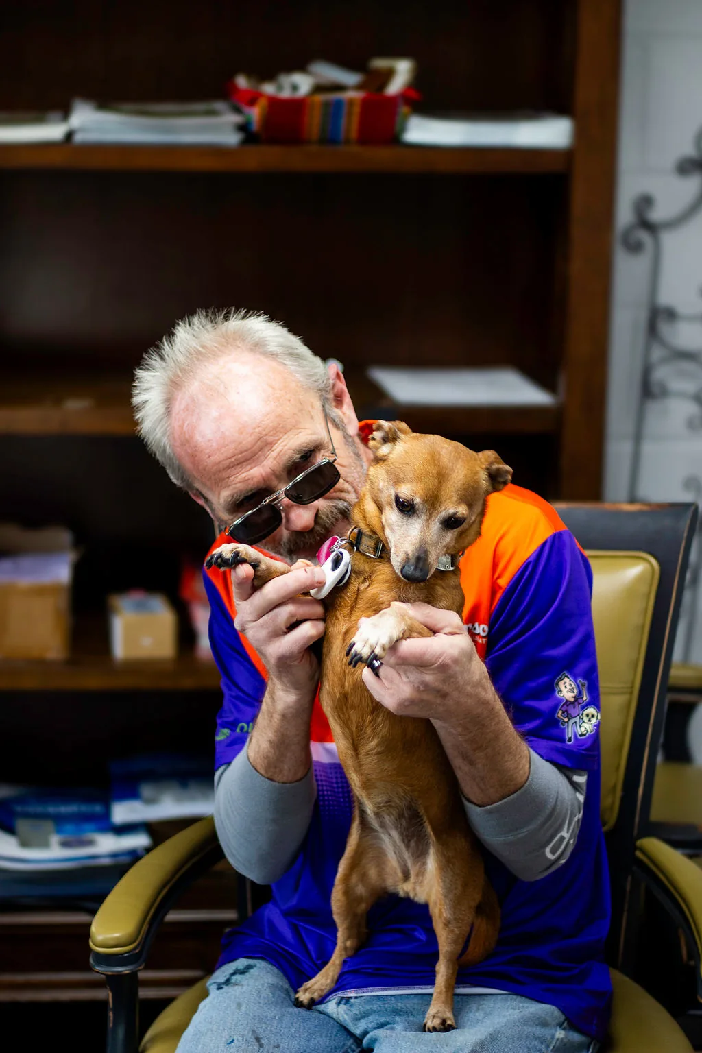 Anderson team member in sunglasses cuddling a small brown dog at the office