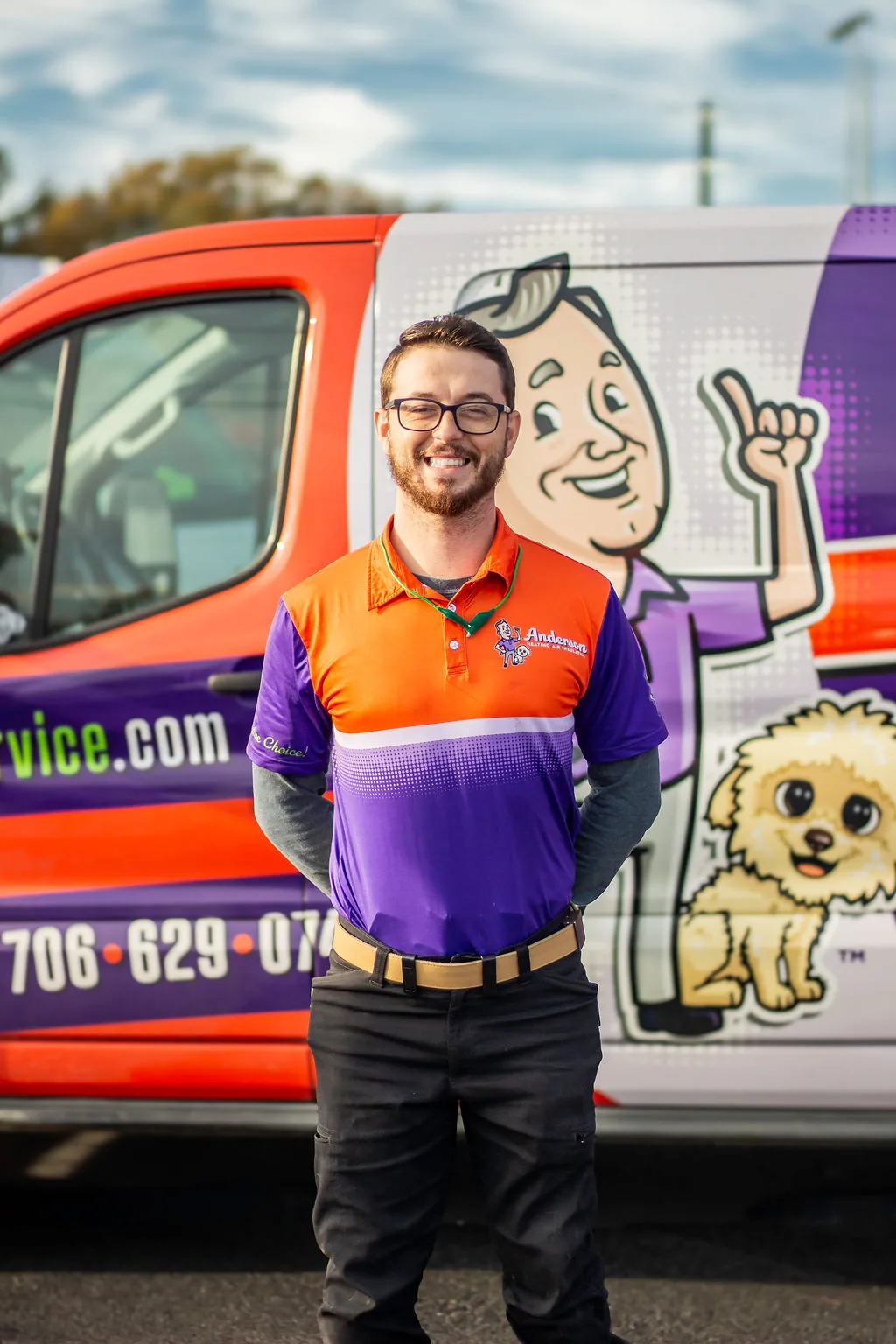 Smiling Anderson technician with glasses and a beard in front of a service van