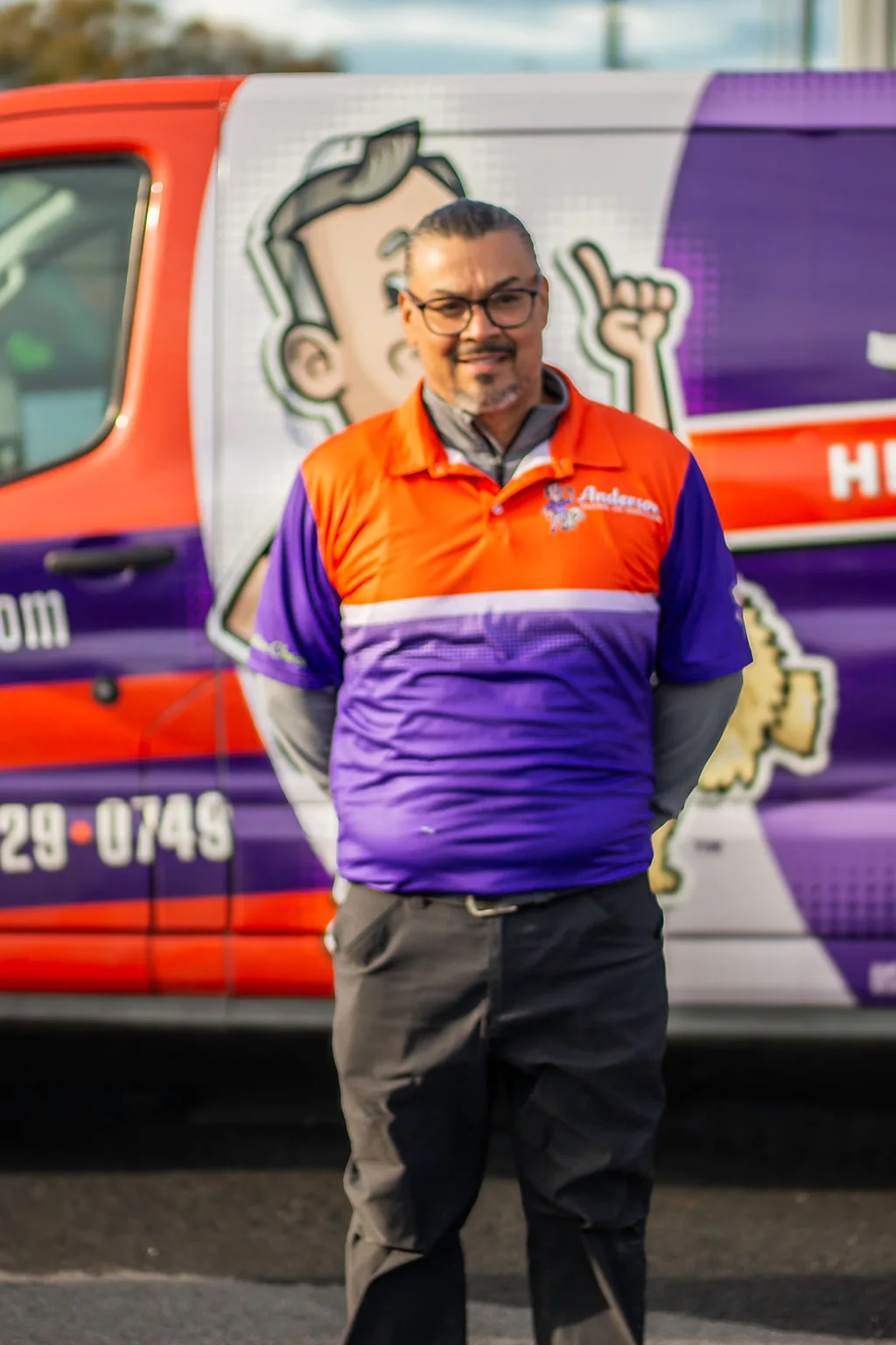 Anderson team member with glasses and a goatee in front of a service van