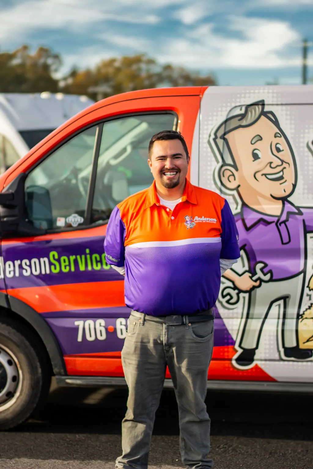 Anderson team member with a goatee smiling in front of a service van