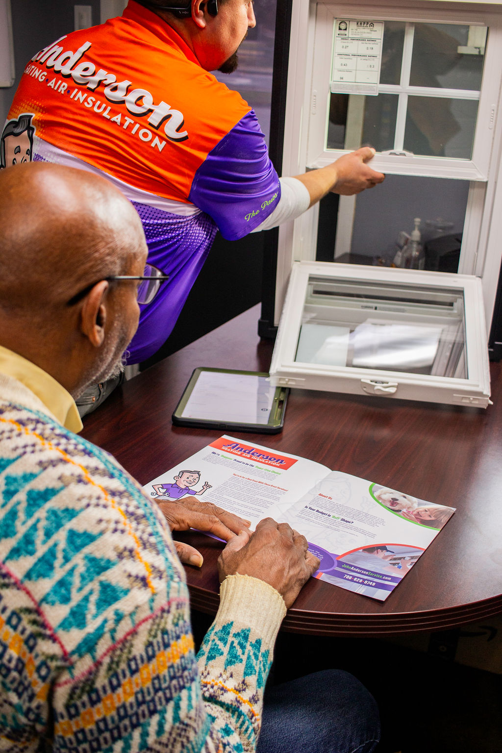 Anderson Heating, Air & Insulation team member walking a customer through window options and financing brochure in the Calhoun office — clear, no-pressure presentation of financing tiers and rebate-eligible projects.