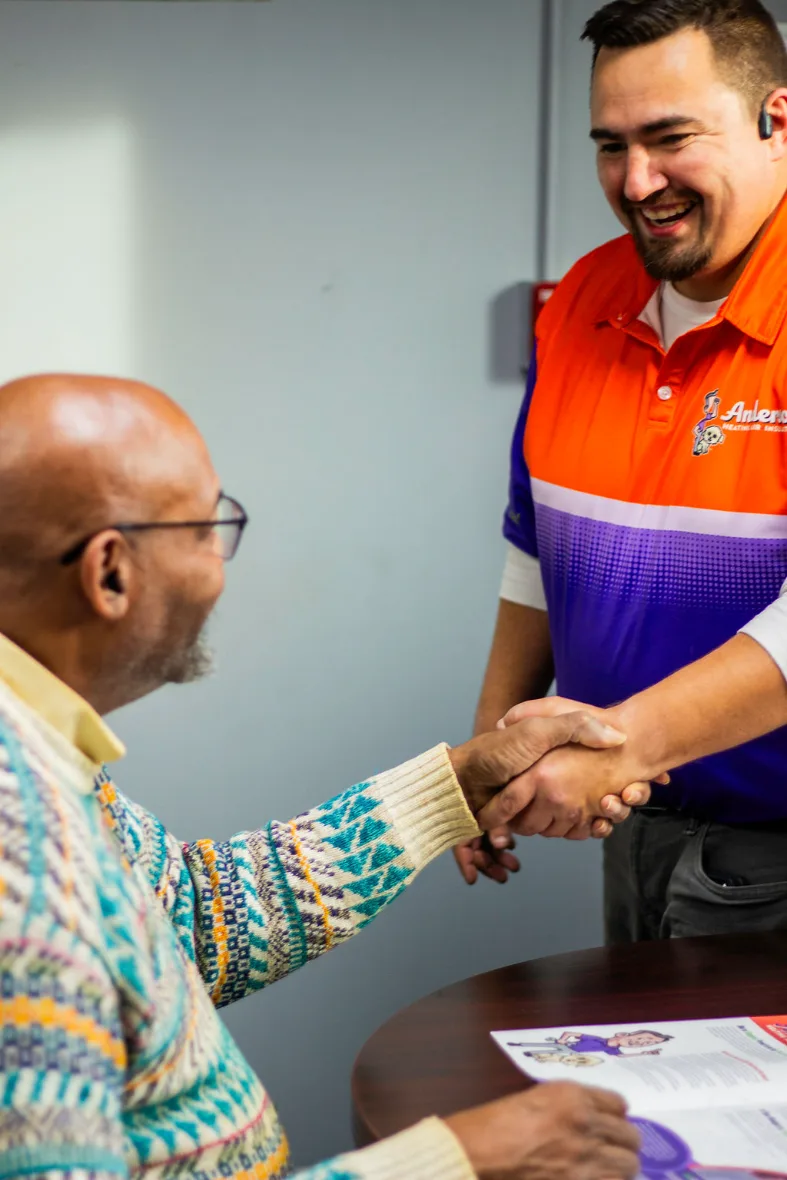 An Anderson comfort advisor shaking hands with a homeowner after an in-home consultation