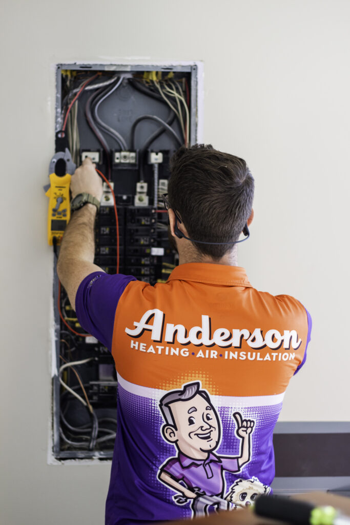 Anderson Heating technician performing electrical diagnostics and safety checks on a commercial service panel.